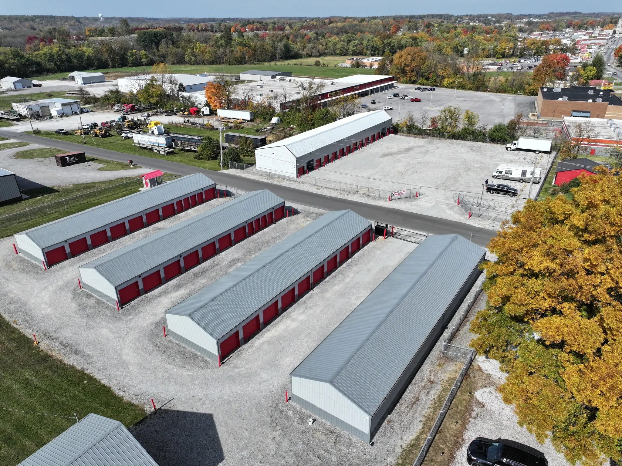 Aerial view of a self-storage facility in Salem with rows of red and gray storage units and a small office building. The spacious design and secure layout make it ideal for all storage needs, including climate-controlled options.