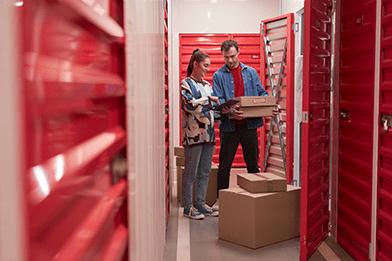 Man and woman at storage box, looking at cardboard boxes.